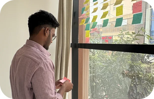 Student organising user research notes on a glass wall
